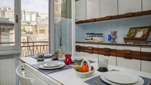 Una cocina moderna con armarios blancos, un estante de madera y vistas a edificios a través de un ventanal grande.