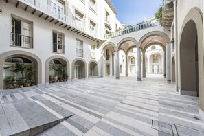 A spacious courtyard with a tiled floor, multiple arches, and columns. - Luxury Gattopardo Loft - Lago Design by Wonderful Italy (Palermo)