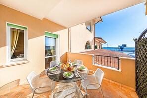 Ein Balkon mit einem runden Glastisch, gedeckt für ein Essen, umgeben von weißen Netzsesseln.