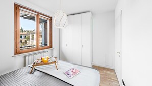 A bedroom with a bed, a window, a radiator, a white wardrobe, and a hanging light fixture. - La Piopa 2 20 in Polpenazze del Garda (Polpenazze del Garda)