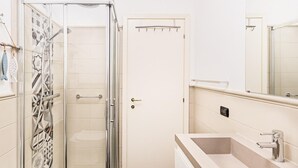 A modern bathroom with a glass-enclosed shower, a large sink, and a door with a towel rack. - La Piopa 2 20 in Polpenazze del Garda (Polpenazze del Garda)