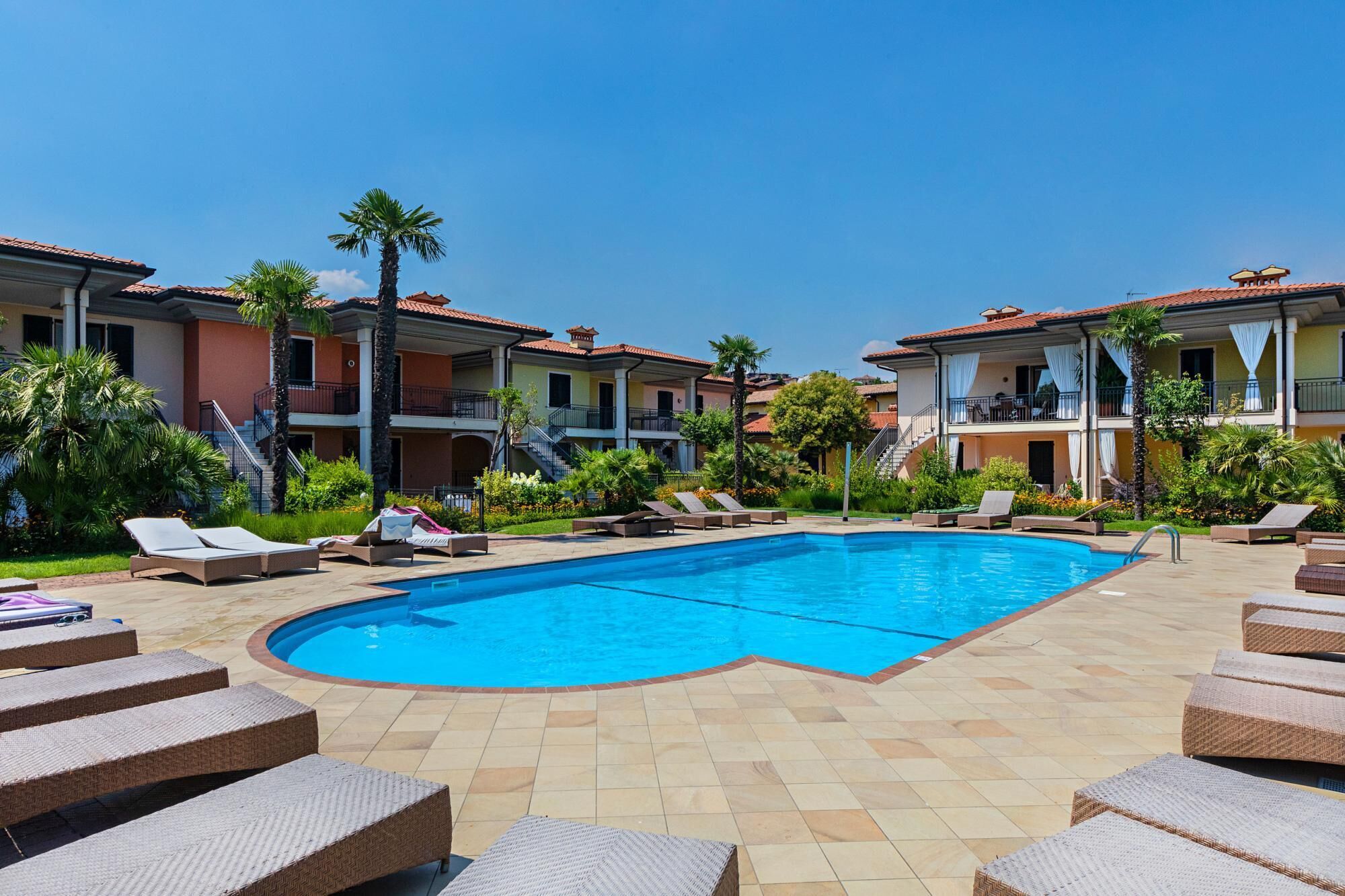 A pool area with lounge chairs and a swimming pool surrounded by buildings with balconies.