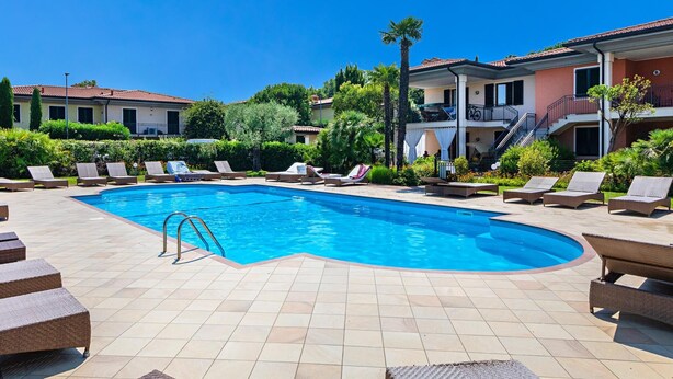 A swimming pool with lounge chairs and a tiled deck. - La Piopa 2 20 in Polpenazze del Garda (Polpenazze del Garda)