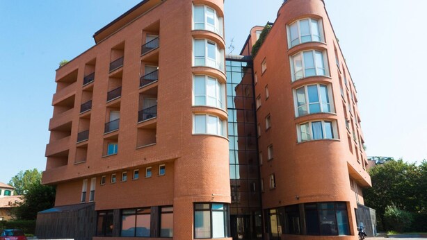 A modern multi-story building with a curved facade, large windows, and balconies. - Massarenti 14 a Porta S Vitale by Wonderful Italy (Bologna)