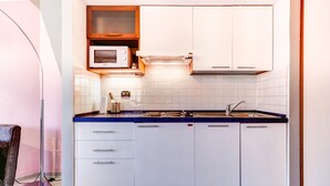 A modern kitchen with white cabinets, a blue countertop, and a microwave. - Massarenti 14 a Porta S Vitale by Wonderful Italy (Bologna)