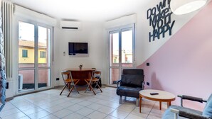 A spacious living area with a dining table, chairs, a sofa, and a TV mounted on the wall. - Massarenti 14 a Porta S Vitale by Wonderful Italy (Bologna)