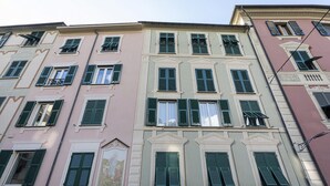 A multi-story building with a classical architectural style, featuring symmetrical window designs and green shutters.
