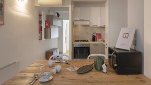 A compact kitchen with white cabinets, a wooden dining table, and a black refrigerator.