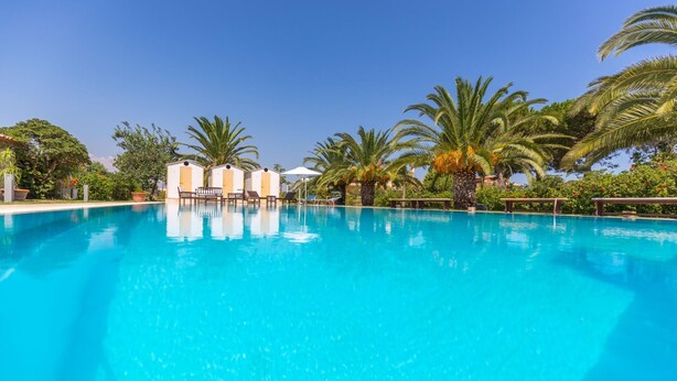 A clear blue pool with lounge chairs and palm trees. - Villa Arenella con Piscina by Wonderful Italy (Syracuse)