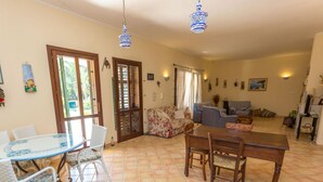 A spacious living room with a dining area, large windows, and a view of the outdoors. - Villa Arenella con Piscina by Wonderful Italy (Syracuse)
