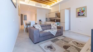 A modern living room with a grey sofa, a patterned rug, and a wooden ceiling.