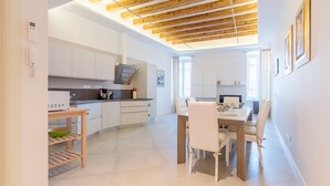 A modern kitchen with white cabinets, a wooden ceiling, and a dining area with a table and chairs.