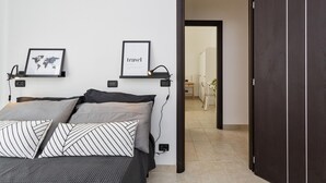 Une chambre à coucher moderne avec un lit, une carte du monde et un tableau encadré sur le thème du voyage accroché au mur.