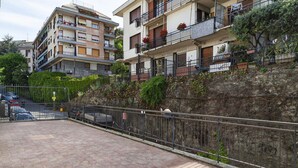 Un immeuble résidentiel à plusieurs étages, doté de balcons, d  ’un mur de soutènement en pierre et d’une zone pavée à l’avant.