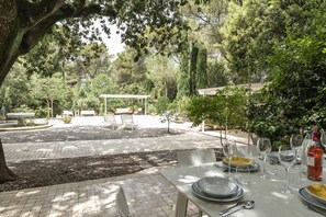An outdoor dining area with a table set for a meal, surrounded by trees and a pergola. - Villa Manfredi con Piscina by Wonderful Italy (Fasano)