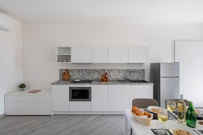 A modern kitchen with white cabinetry, a granite countertop, a built-in oven, and a stainless steel refrigerator. - San Carlo Borromeo 2 by Wonderful Italy (Soiano del Lago)