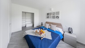 A modern bedroom with a bed, bedside tables, a wall-mounted artwork, and a visible closet. - San Carlo Borromeo 2 by Wonderful Italy (Soiano del Lago)