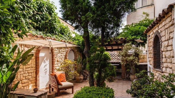 A courtyard with a stone wall, a wooden bench, and potted plants. - Villa Amun con Giardino by Wonderful Italy (Riposto)