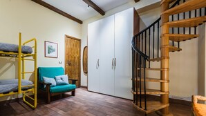 A room with bunk beds, a sofa, a wardrobe, and a wooden spiral staircase. - Villa Amun con Giardino by Wonderful Italy (Riposto)