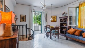 A spacious living room with a dining area, a staircase, and a view of greenery outside. - Villa Amun con Giardino by Wonderful Italy (Riposto)