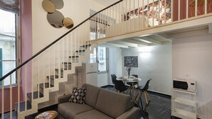 Un interior moderno con una escalera, un sofá, un comedor y un microondas sobre un carrito.