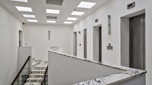 A modern hotel lobby with a marble staircase, elevators, and a glass railing. - Deluxe Apartment - Avio by Wonderful Italy (Genoa)