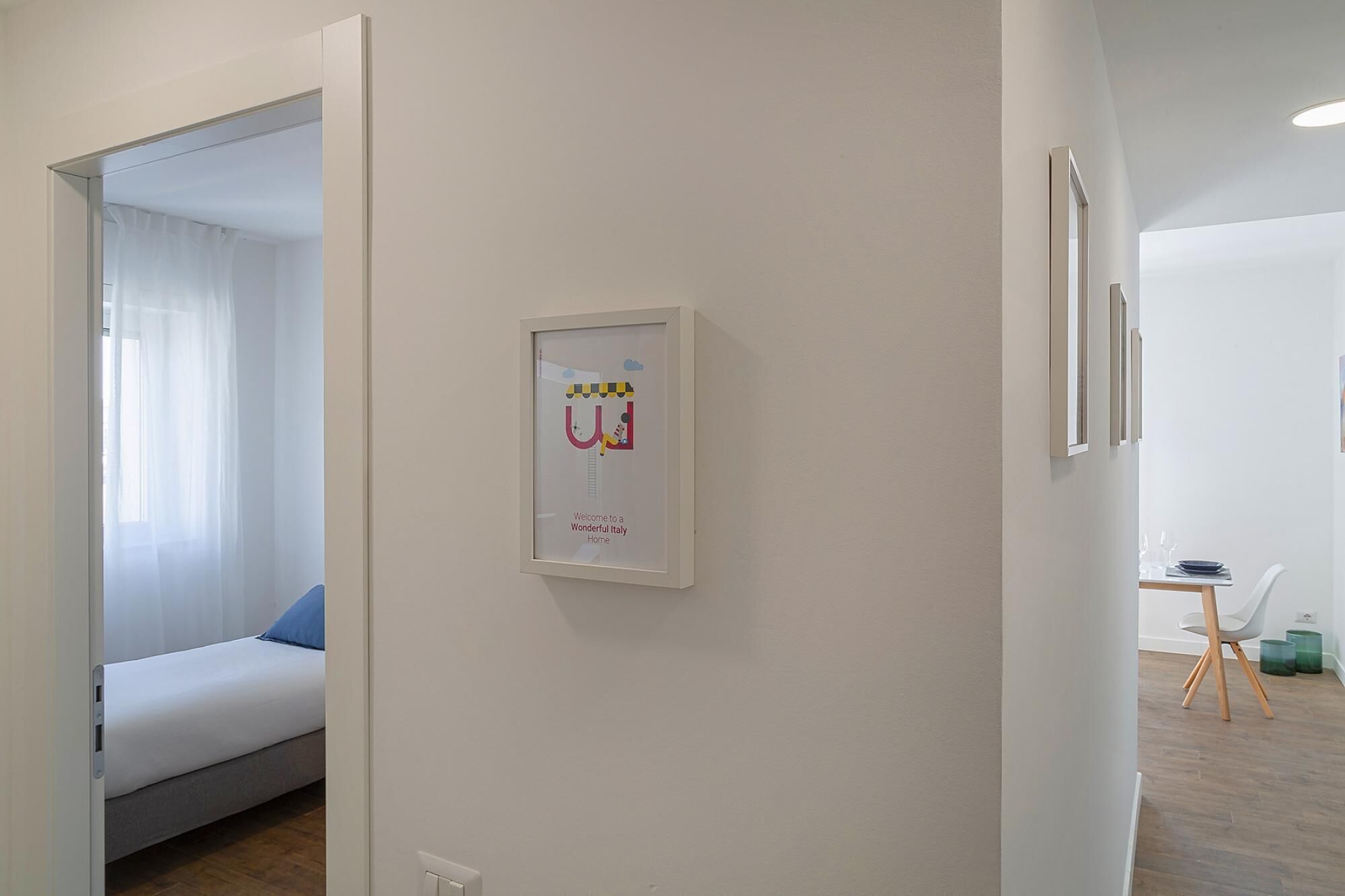 Une chambre moderne avec un lit, un panneau d’accueil encadré et un bureau avec une chaise.