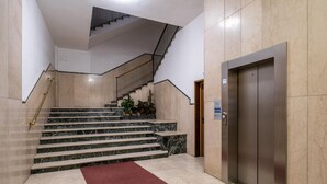 A modern interior with marble stairs, a red carpet, and a metallic elevator. - Studio Grey al Parco Montagnola by Wonderful Italy (Bologna)
