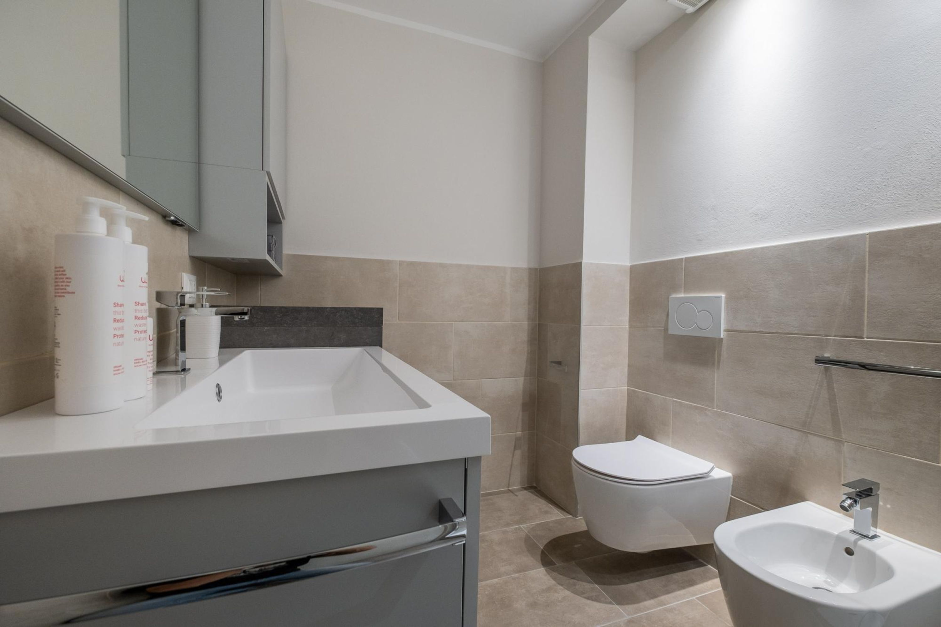 A modern bathroom with a white sink, a toilet, and a bidet.