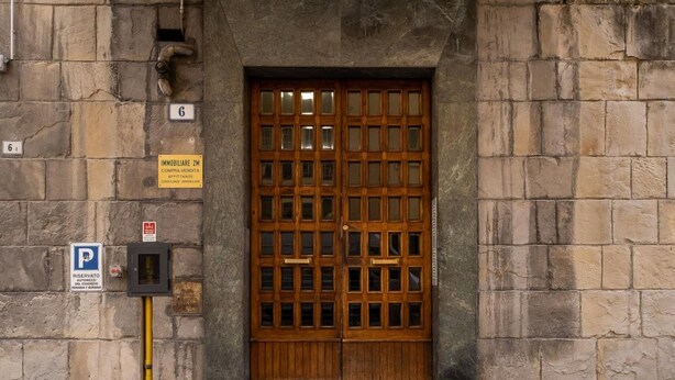 A building entrance with a wooden door, a parking sign, and a fire hydrant. - Studio Grey al Parco Montagnola by Wonderful Italy (Bologna)