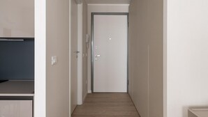 A narrow hallway with a wooden floor, white walls, and a door at the end. - Studio Grey al Parco Montagnola by Wonderful Italy (Bologna)