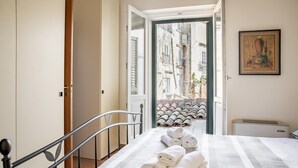 A hotel room with a bed, a view of the street outside, and a painting on the wall. - Duplex sul Porto Grande by Wonderful Italy (Syracuse)