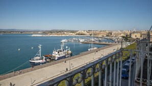 A harbor with boats docked, a clear sky, and a cityscape in the background. - Duplex sul Porto Grande by Wonderful Italy (Syracuse)