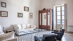 A modern living room with a white sofa, a glass coffee table, and a patterned floor. - Duplex sul Porto Grande by Wonderful Italy (Syracuse)