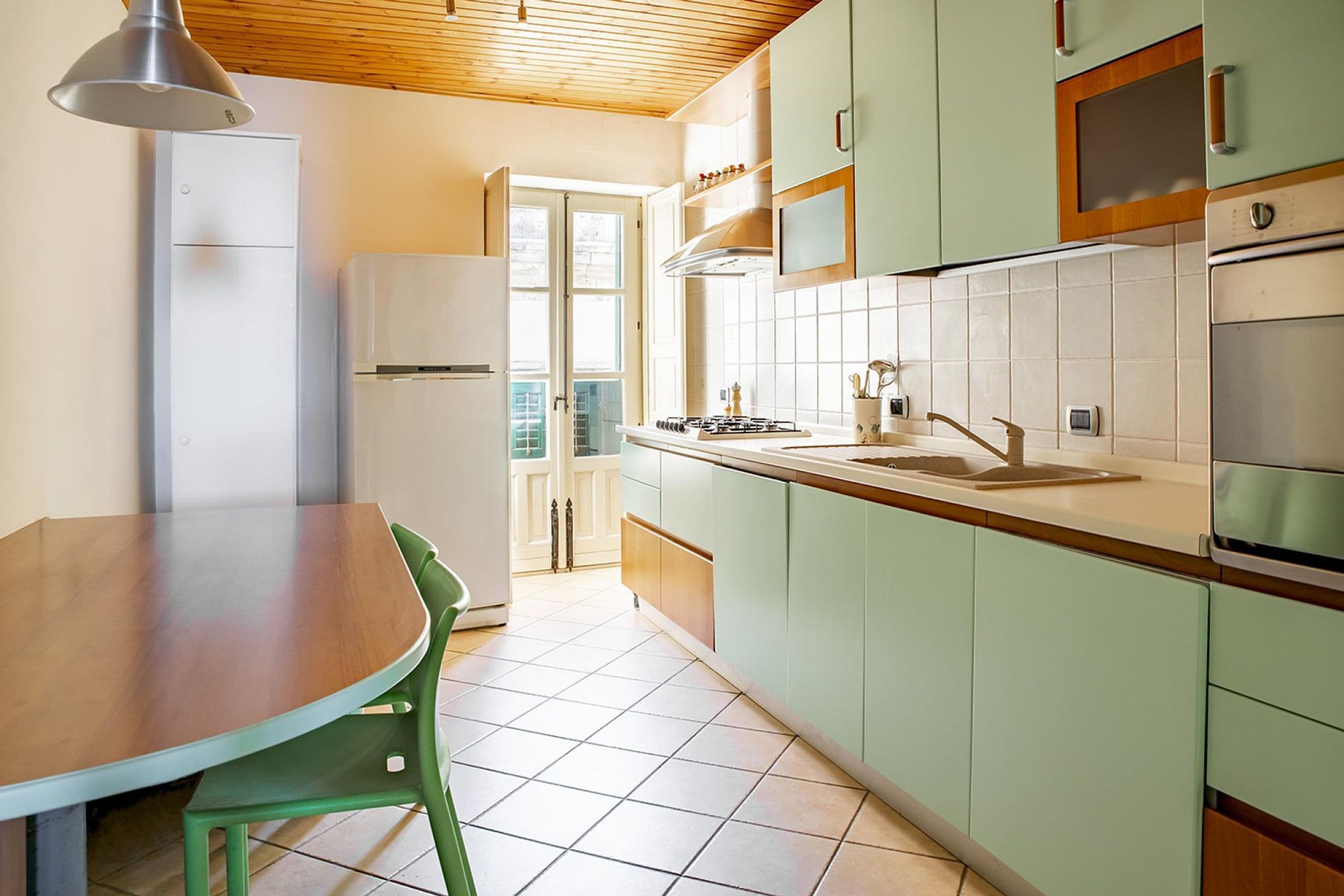 A kitchen with a dining table and chairs, a refrigerator, a stove, and cabinets.
