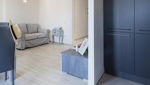 Un salon moderne avec un canapé gris, une petite table d’appoint et une armoire sombre.