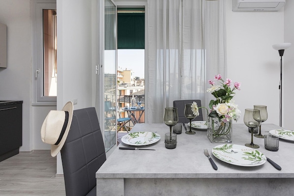 Enjoy meals with family and friends at this dining area, featuring a table for four, wine glasses, and a vase with fresh flowers.