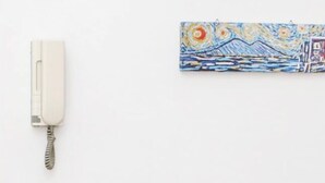 Uma área de refeições moderna com uma mesa posta para dois, um telefone e um quadro na parede.