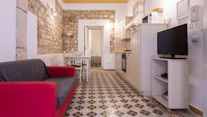 A compact living space with a kitchenette, a dining area, and a seating area with a red sofa.