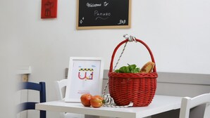 A white table with a red basket containing bread and lettuce, a framed picture with a cartoon character, and a chalkboard with "Welcome to Panaro" written on it. - O Panaro ai Quartieri Spagnoli (Naples)