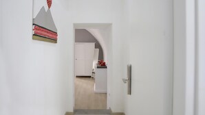 A hallway leading to a kitchen with white cabinets and a door. - O Panaro ai Quartieri Spagnoli (Naples)
