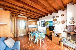 Una cocina rústica y acogedora con vigas de madera, una mesa de comedor dispuesta para cuatro personas y varios platos decorativos en la pared.