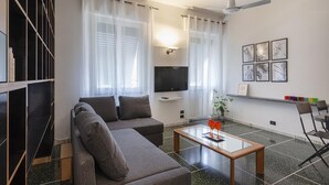 A modern living room with a sofa, a coffee table, a TV, and a ceiling fan.