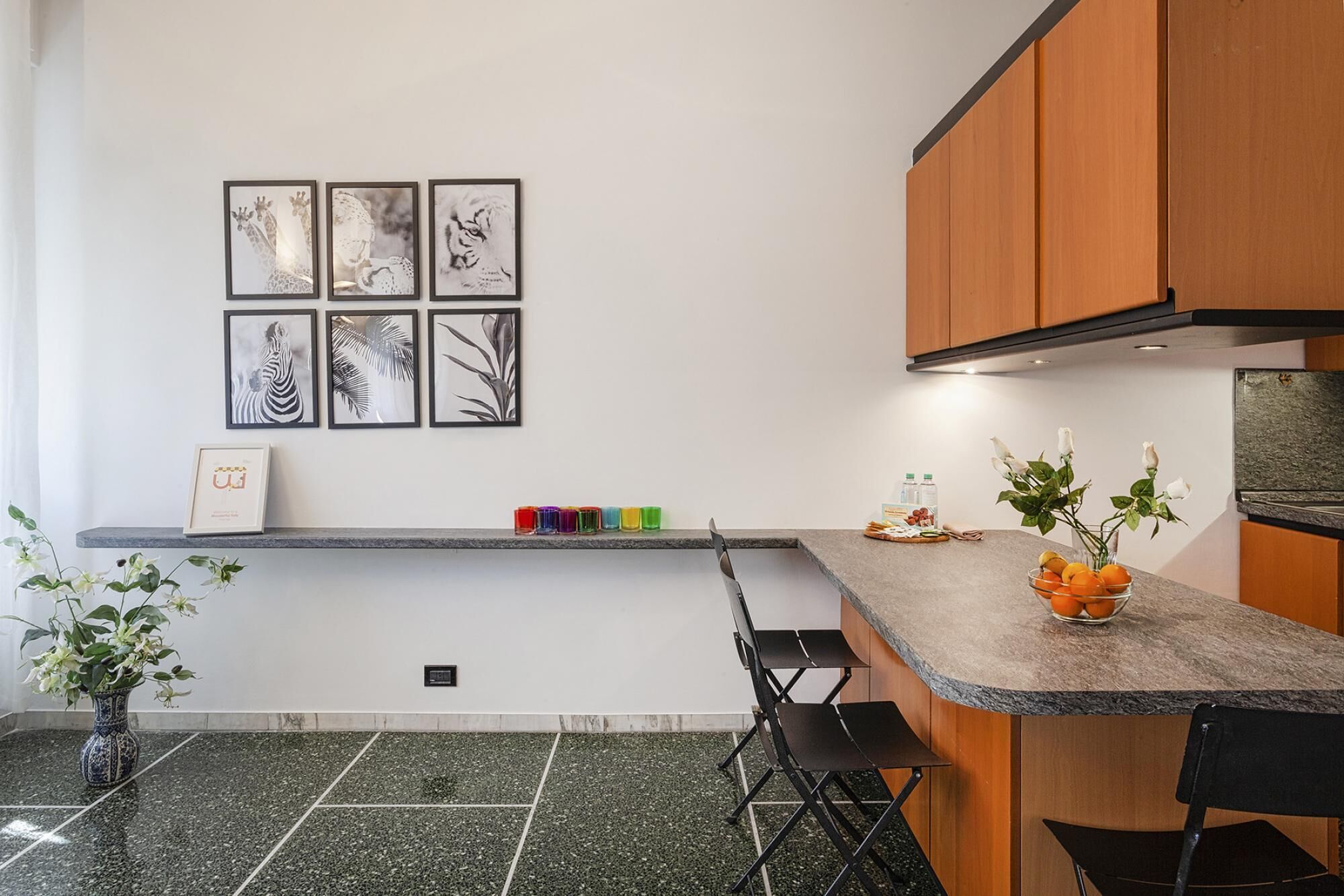 A modern kitchen with a granite countertop, wooden cabinets, and a dining area with a bench.