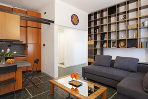 A modern living room with a grey sofa, a coffee table, and a bookshelf filled with books and decorative items. - S Margherita Apartment in the City Center (Santa Margherita Ligure)