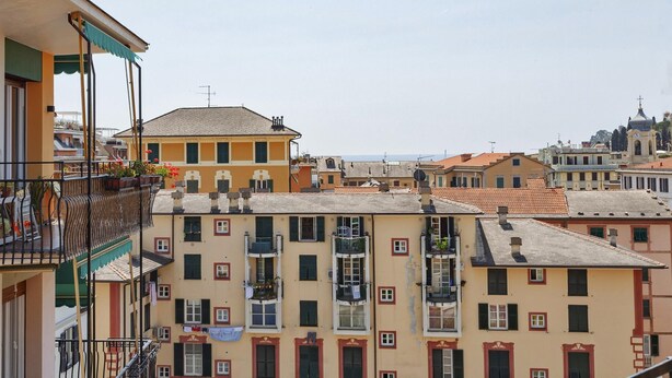 A row of multi-story buildings with balconies, some with plants.