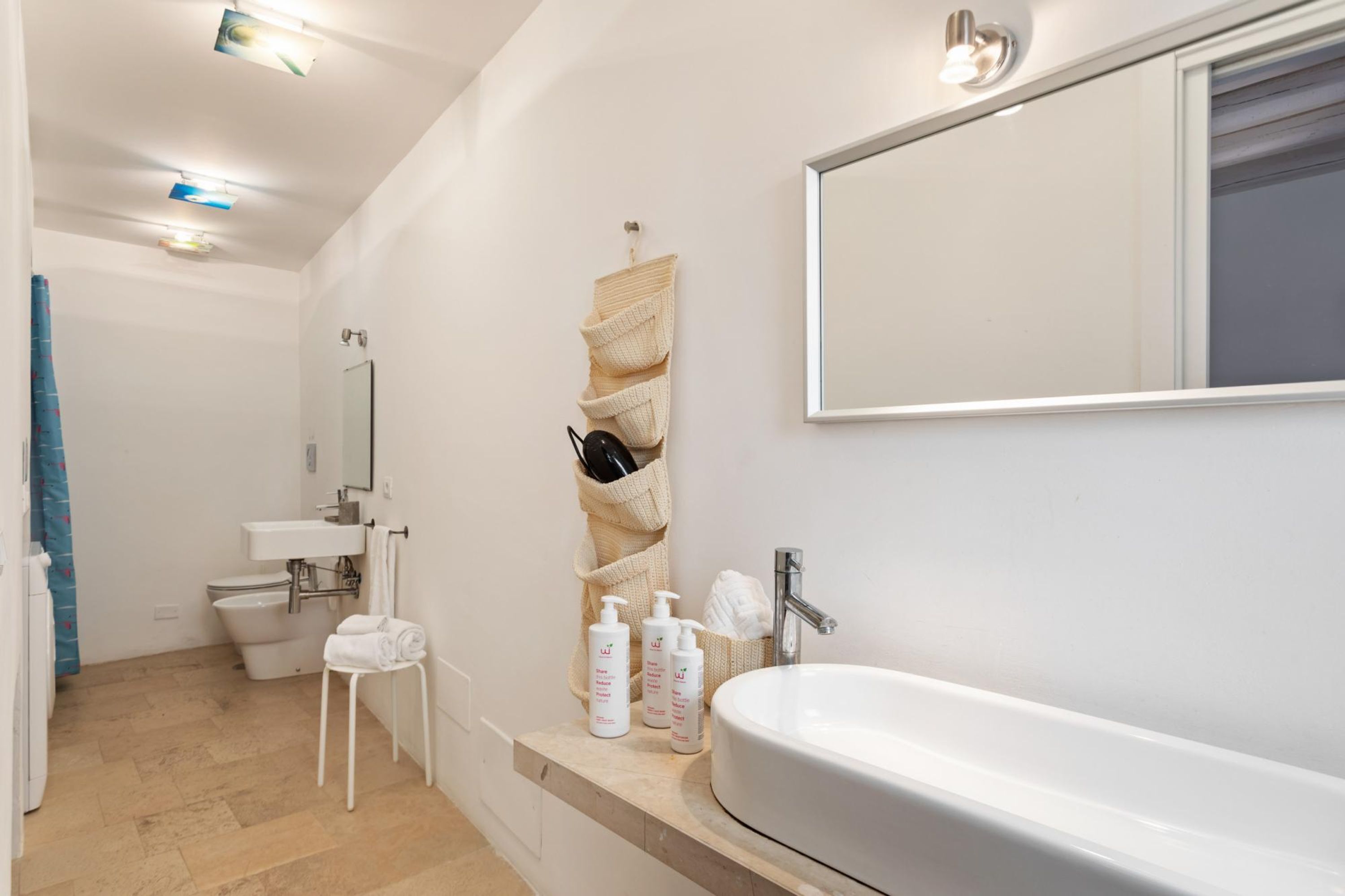 Ein modernes Badezimmer mit einem großen Waschbecken, einem Spiegel und einem Handtuchhalter.