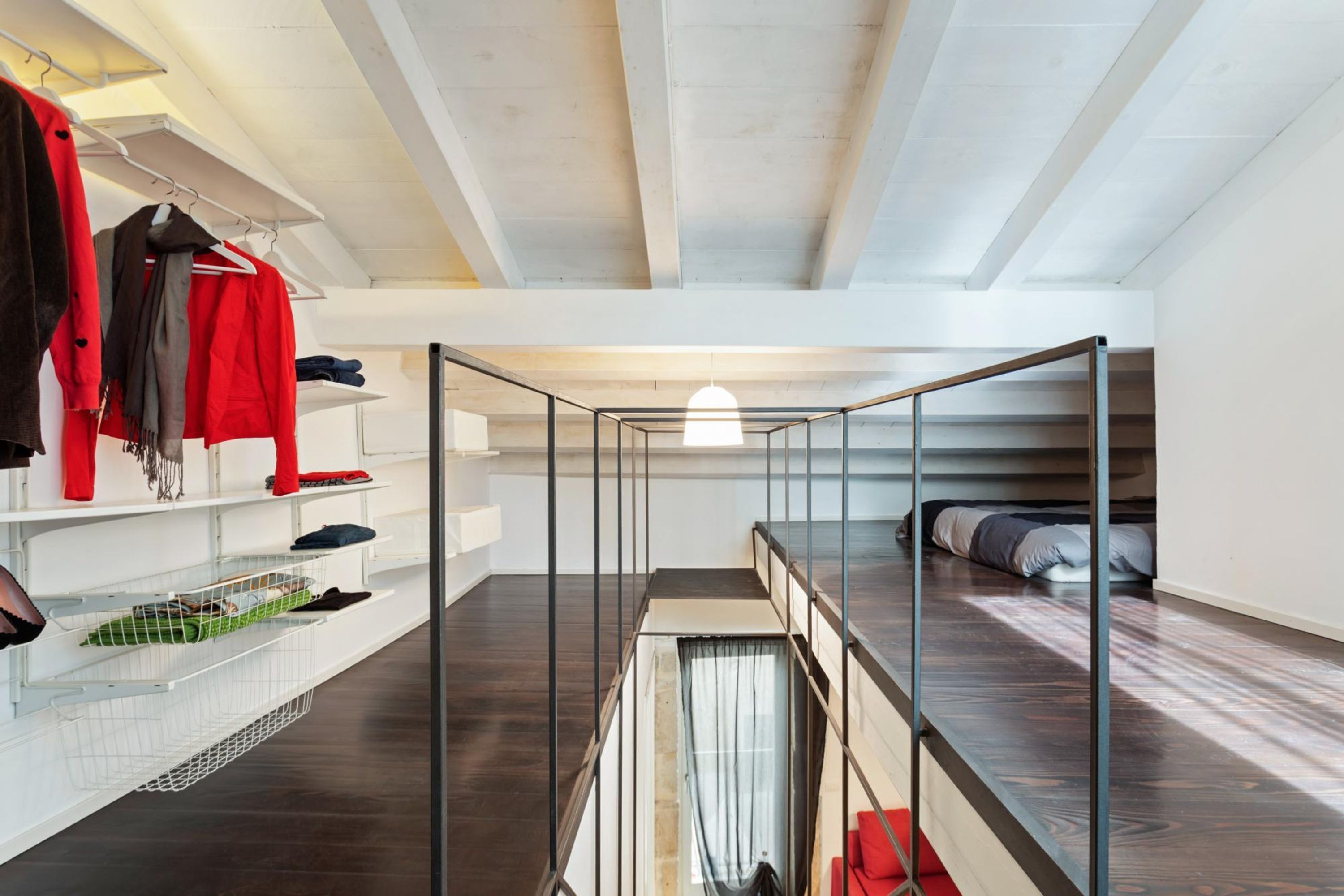 Une chambre de style loft moderne, dotée d’un plafond en verre, d’un lit superposé et d’étagères intégrées pour ranger les vêtements et autres effets personnels.