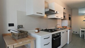 A modern kitchen with white cabinetry, a gas stove, an oven, and a sink.