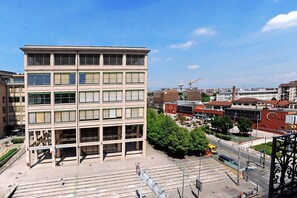 A multi-story building with a central courtyard, surrounded by other buildings and a construction site in the background.